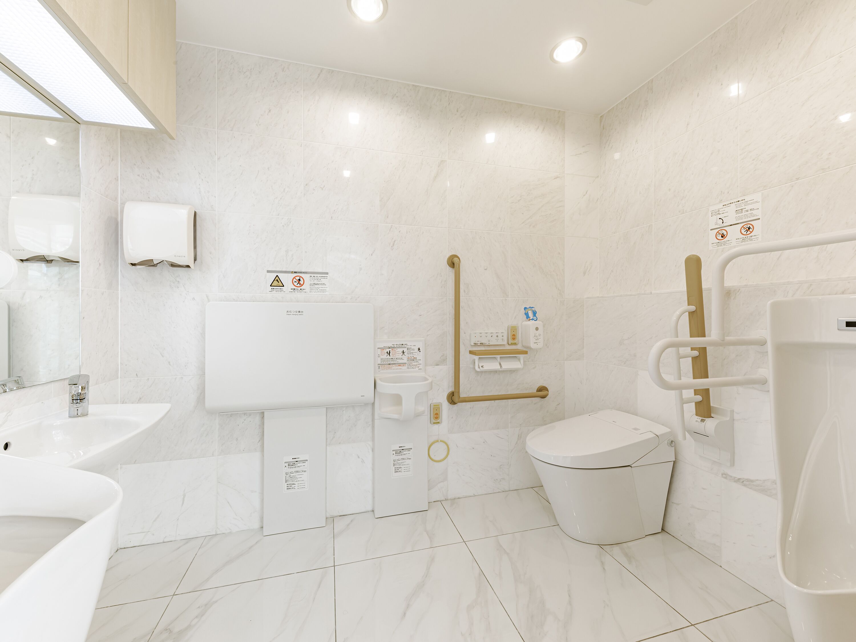 A modern bathroom with a toilet, bidet, and hand dryer.