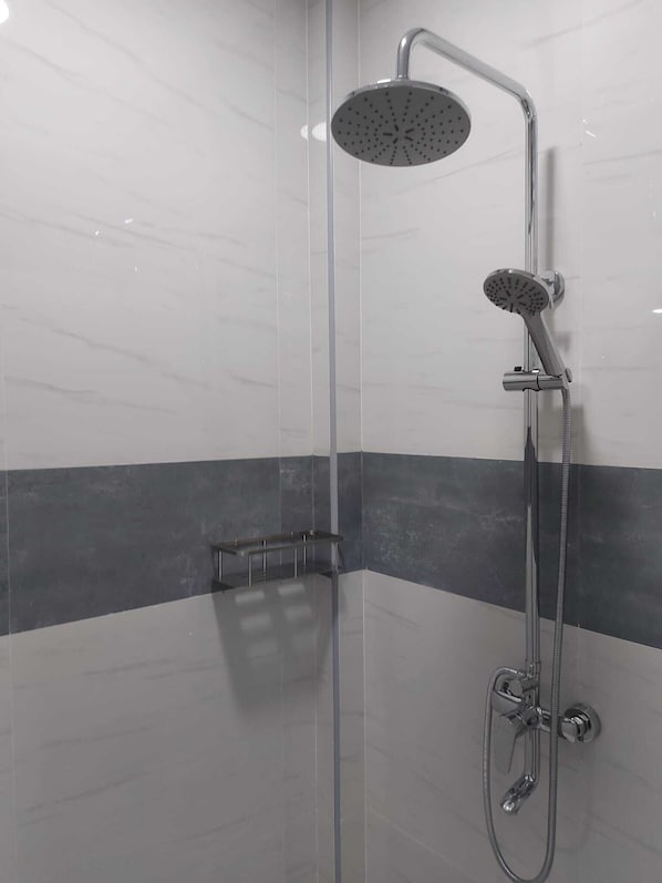 Ducha moderna con cabezal de ducha de mano y cabezal de ducha fijo montado en una pared con diseño de azulejos grises y blancos.