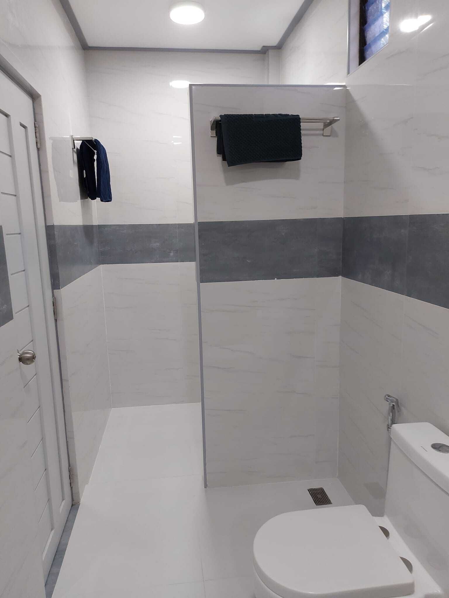 A modern bathroom with a shower, toilet, and towel rack.