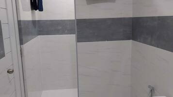 A modern bathroom with a shower, toilet, and towel rack.