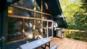 A wooden deck with a picnic table and a grill area.