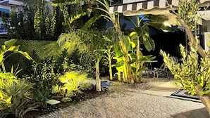 A courtyard with a paved area, a decorative stone pattern, and various tropical plants. - Villa Lui Hotel Alaçatı (Cesme)