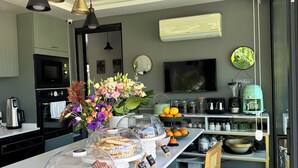 A modern kitchen with a central island, overhead pendant lighting, and a built-in oven. - Villa Lui Hotel Alaçatı (Cesme)
