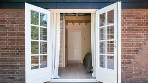 Una habitación con suelo de madera, una puerta blanca y una pared de ladrillo.