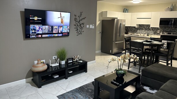 A modern living room with a flat-screen TV, a coffee table, and a sofa.