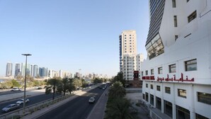 A modern urban street with a multi-story building featuring a prominent red sign. - oyo 123 (Manama)