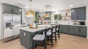 A modern kitchen with a central island, bar stools, and pendant lighting. - Casa Paradiso|Private Pool, Firepit & Putt. Green (Scottsdale)