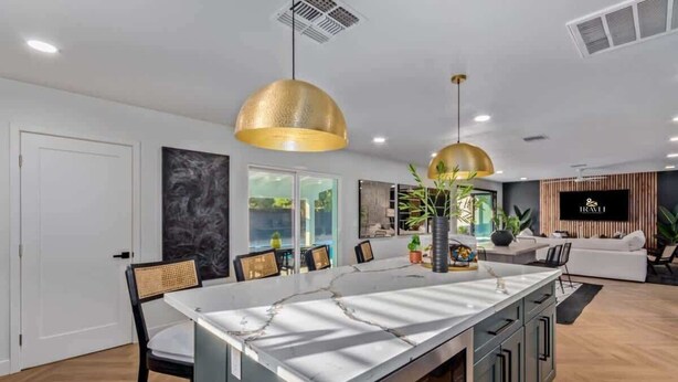 A modern kitchen with a central island, pendant lighting, and a view to the living area. - Casa Paradiso|Private Pool, Firepit & Putt. Green (Scottsdale)