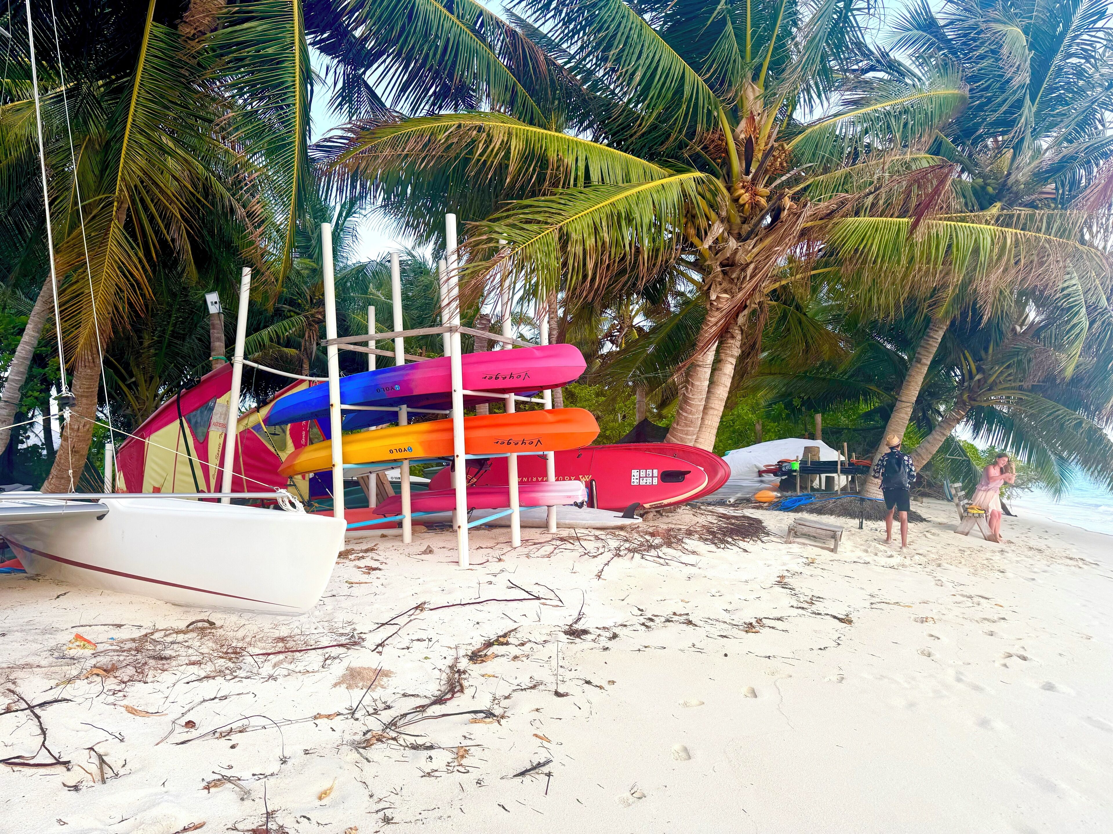 A beach with a row of colorful kayaks and a white boat.