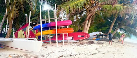A beach with a row of colorful kayaks and a white boat.