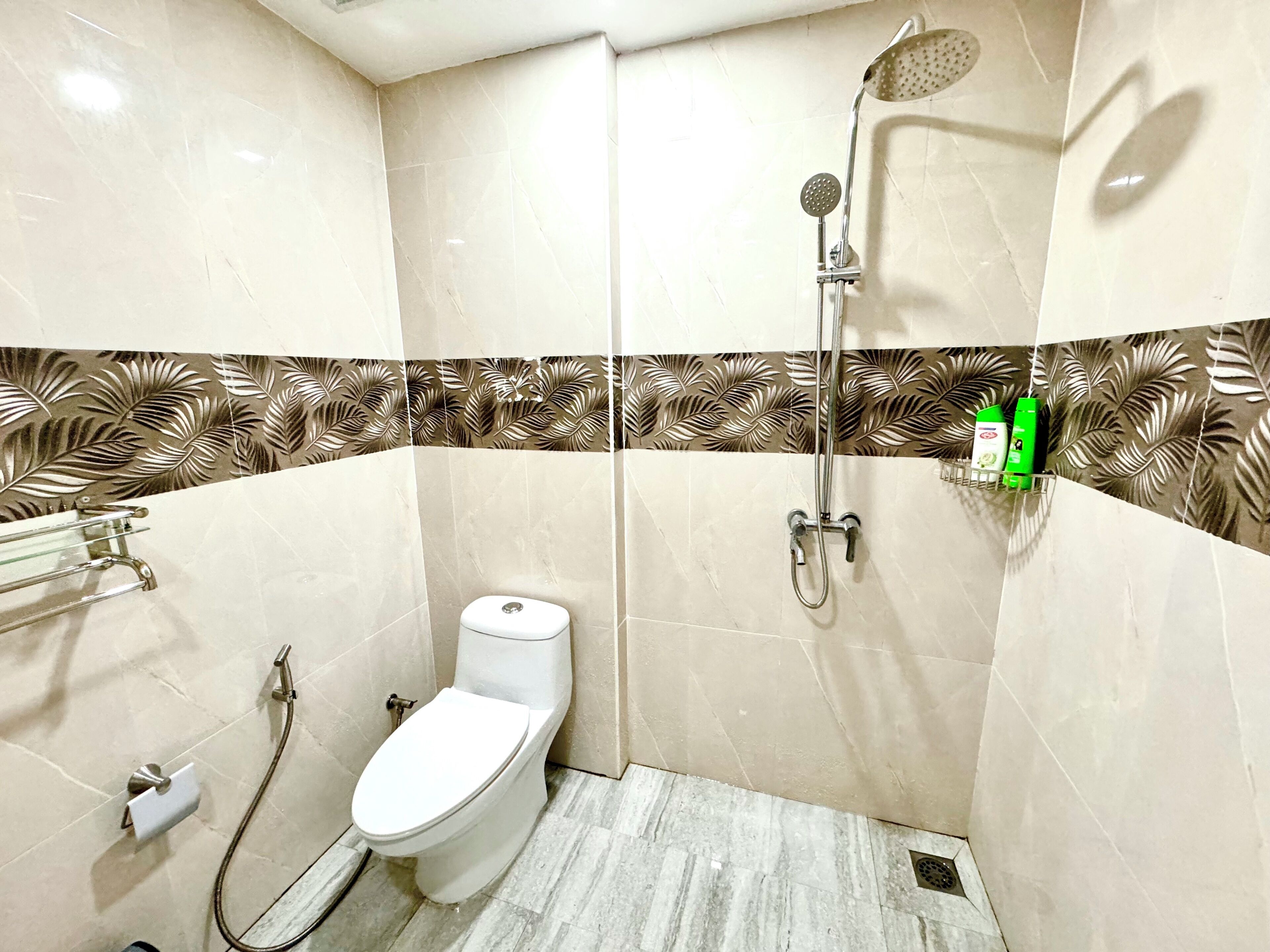 A small, modern bathroom with a toilet, shower, and a shelf with toiletries.
