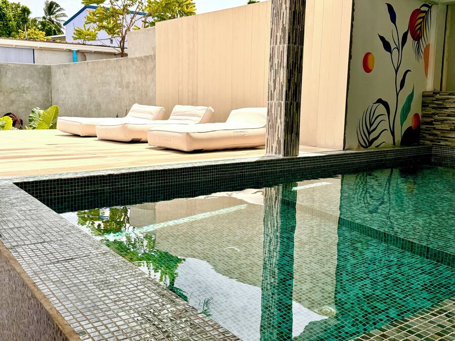 A modern outdoor pool area with lounge chairs and a tiled edge.