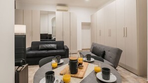 A modern kitchen with a dining area, equipped with a coffee machine, a kettle, and a fruit bowl.
