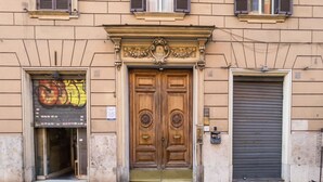 Un edificio con una puerta doble de madera, una tienda con grafitis coloridos y un toldo cerrado.
