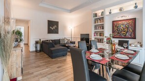 Una sala de estar moderna con un sofá, una mesa de comedor lista para seis comensales y una estantería.