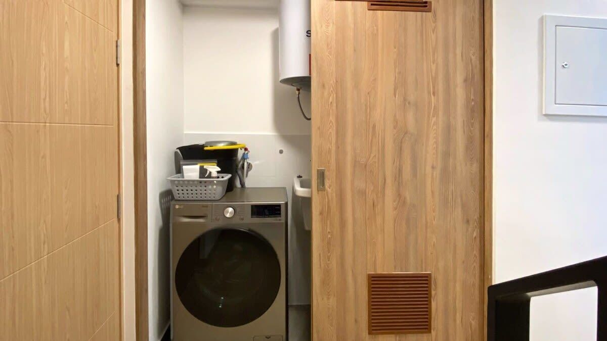 Une buanderie équipée d’un lave-linge et d’un sèche-linge, avec des murs en bois et une bouche d’aération au mur.