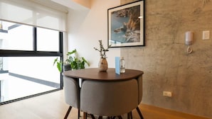 A modern room with a round table, two chairs, a potted plant, a vase, and a framed picture on the wall. - w* | Executive 1BR Duplex in Miraflores (Miraflores)