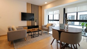 A modern living room with a flat-screen TV, two sofas, a coffee table, and a dining table with chairs. - w* | Executive 1BR Duplex in Miraflores (Miraflores)