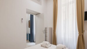Ett hotellrum med en säng, en dörr som leder till badrummet och en tv som är monterad på väggen.
