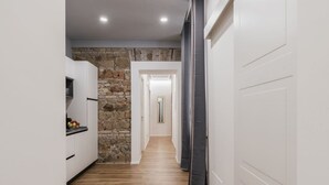 Un couloir étroit avec un mur en pierre, des armoires blanches et un plancher en bois.