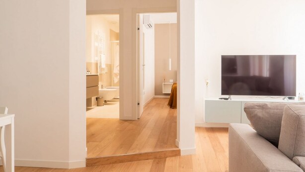 A modern living room with a flat-screen TV, a sofa, and a wooden floor. - The Best Rent - Apartment in Buenos Aires district (Milano)