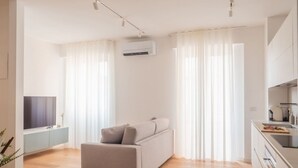 A modern living room with a sofa, a TV, and a kitchen area with a stove and cabinets. - The Best Rent - Apartment in Buenos Aires district (Milano)
