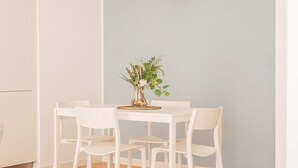 A dining area with a white table and chairs, a vase with flowers, and a light blue wall. - The Best Rent - Apartment in Buenos Aires district (Milano)