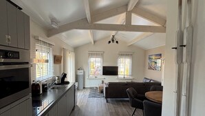 Eine geräumige Küche mit modernen Geräten, ein Essbereich mit rundem Tisch und ein Wohnzimmer mit Sofa und Fernseher.