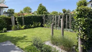 Un jardin bien entretenu, doté d’un chemin pavé, de divers arbustes et d’une clôture en bois.
