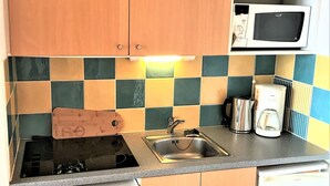 Eine Küche mit Mikrowelle, Kaffeemaschine und einem Messerblock auf der Arbeitsfläche.