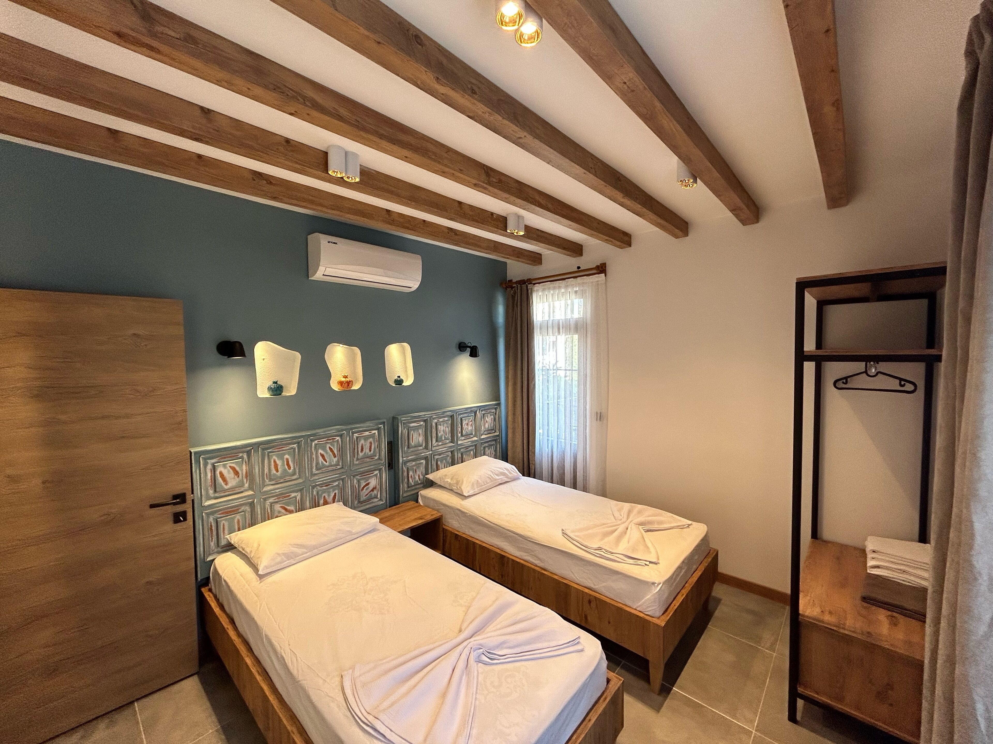 Un dormitorio con dos camas individuales, un armario, un espejo y un perchero.