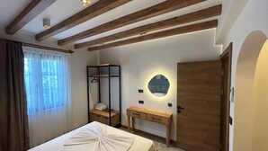Un dormitorio con cama, mesita de noche, espejo, armario y ventana con cortinas.