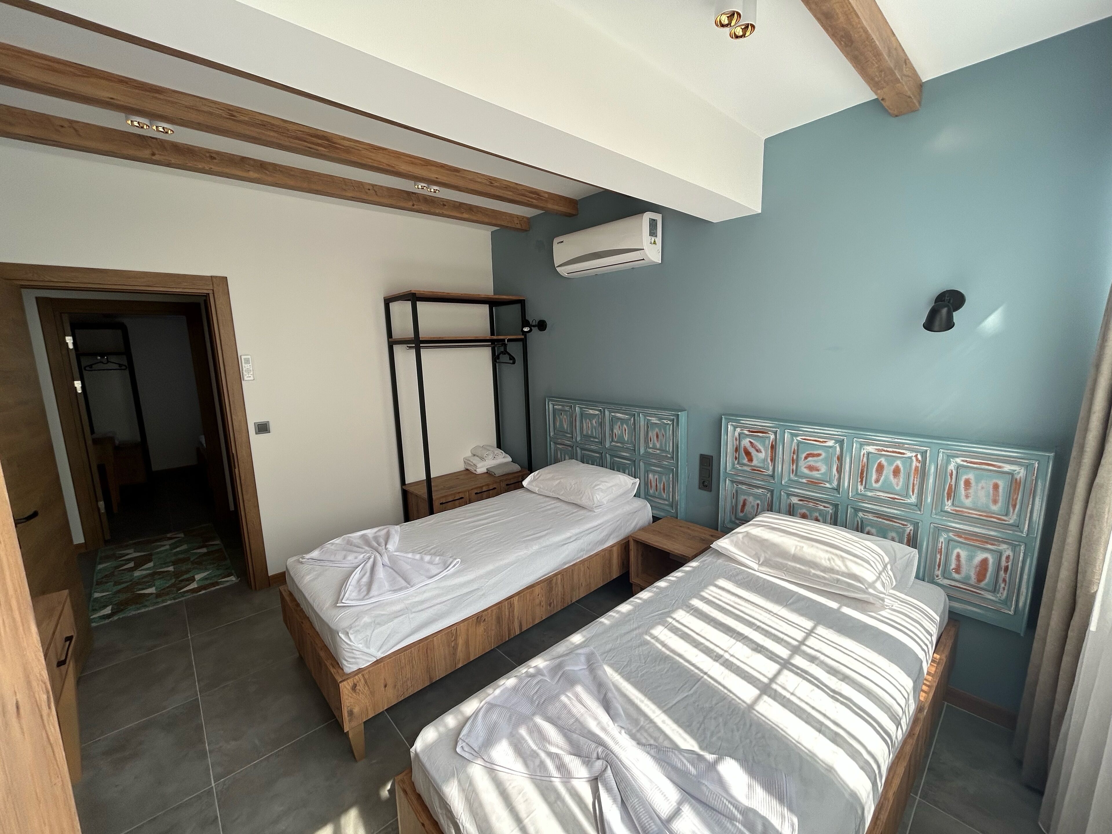 Ein Schlafzimmer mit zwei Betten, einem Holzschrank, einem Deckenventilator und einer Klimaanlage.