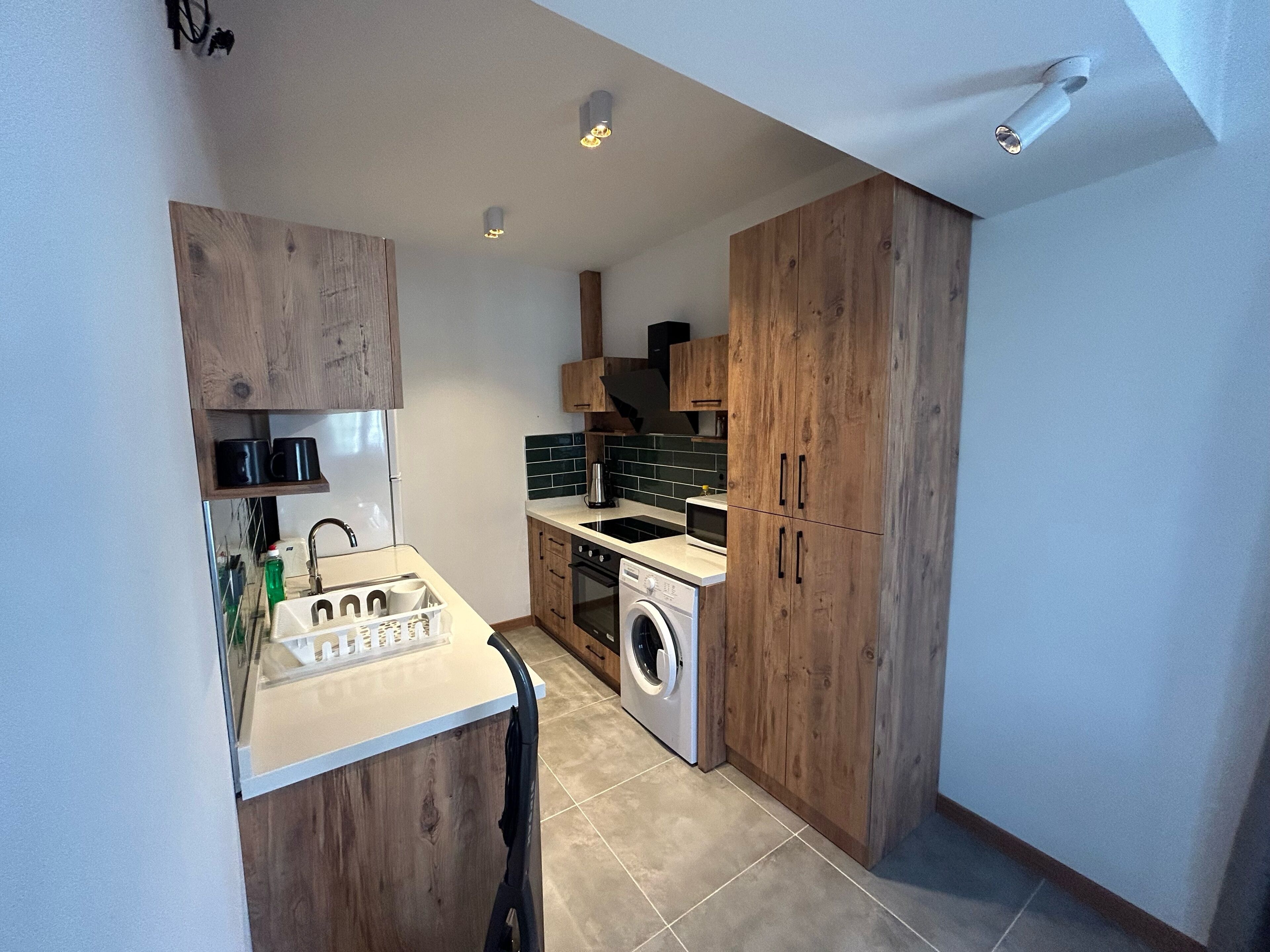 Una cocina compacta con muebles de madera, lavadora y una pequeña encimera.