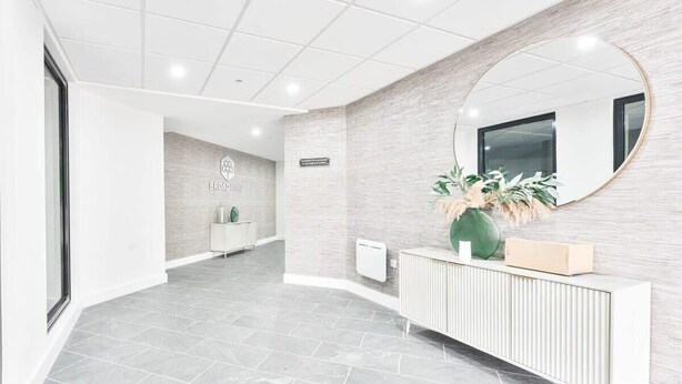 A modern reception area with a tiled floor, a white console, a large mirror, and a wall-mounted sign. - Stylish 2BR Solihull Flat, Quick Train to NEC (Birmingham)