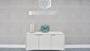 A white cabinet with a textured wall background and a logo above it. - Stylish 2BR Solihull Flat, Quick Train to NEC (Birmingham)