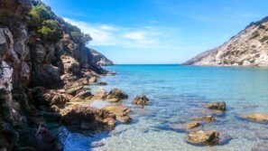 A coastal landscape with rocky terrain and clear blue waters.