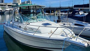 A marina with a white boat docked, featuring a cabin with a green roof, and a bridge in the background. - Cozy Room | Walk to La Placita & Condado Beach (San Juan)
