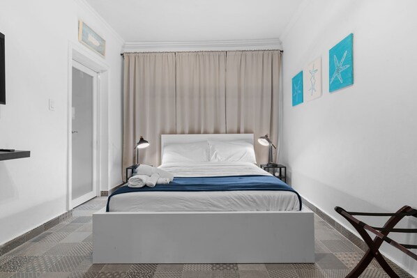 A neatly arranged hotel room with a bed, bedside lamps, a chair, and artwork on the wall.