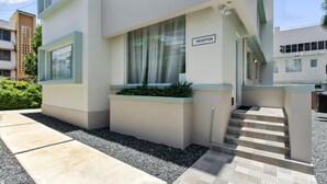 A modern building with a reception area, steps leading to an entrance, and a small garden area.