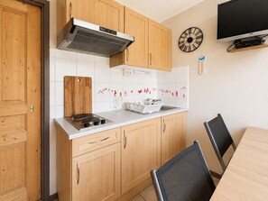Una cucina moderna con mobili in legno, un piano cottura a gas, una cappa aspirante e una zona pranzo con tavolo e sedie.