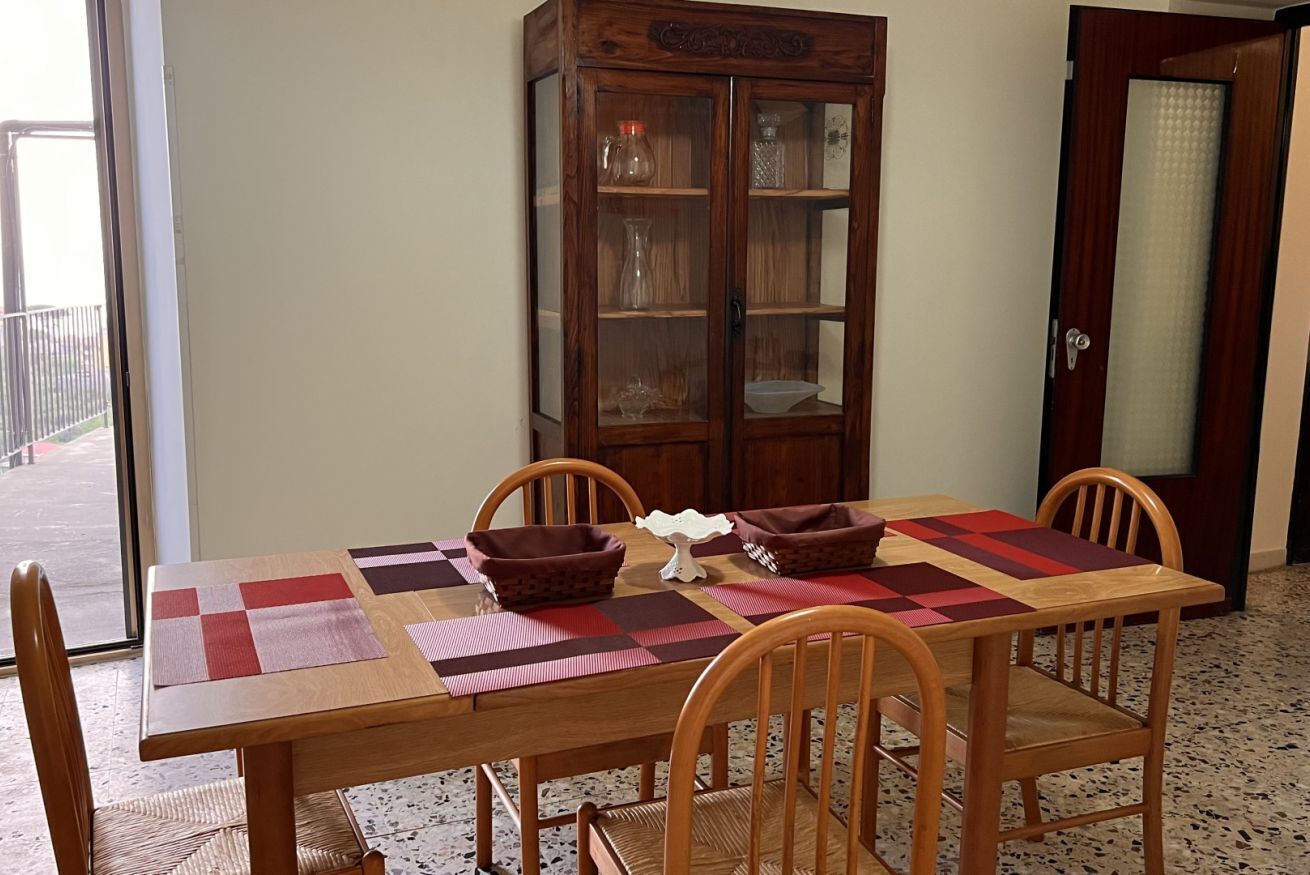 Zona pranzo con tavolo in legno, quattro sedie e una credenza con vetrina.