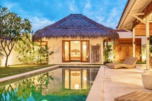 A thatched-roof bungalow with a pool and lounge area. - Villa Folie by Alfred in Bali (Seminyak)