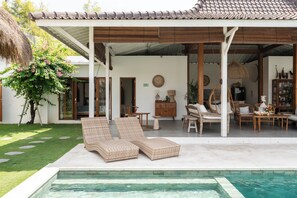 A poolside area with lounge chairs, a covered patio, and a view of the pool. - Villa Folie by Alfred in Bali (Seminyak)