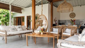 Un vaste espace extérieur aménagé avec des meubles en osier, une table en bois et un luminaire suspendu.