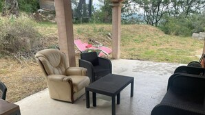 An outdoor patio with a beige leather chair, a black wicker table, and a black sofa. - Villa au Calme (Draguignan)