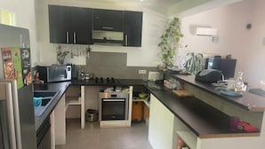 A modern kitchen with dark cabinets, a built-in oven, and a countertop with various appliances and items. - Villa au Calme (Draguignan)