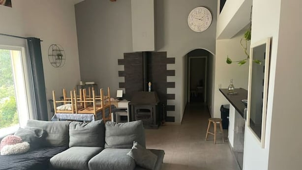 A modern living room with a grey sofa, a fireplace, and a dining area with wooden chairs. - Villa au Calme (Draguignan)