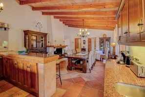 Enjoy cooking and dining in this well-appointed kitchen and dining area, featuring an island with a sink and a wooden table.