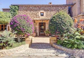 Traditional stone building with a rustic charm, surrounded by lush greenery and a paved pathway.